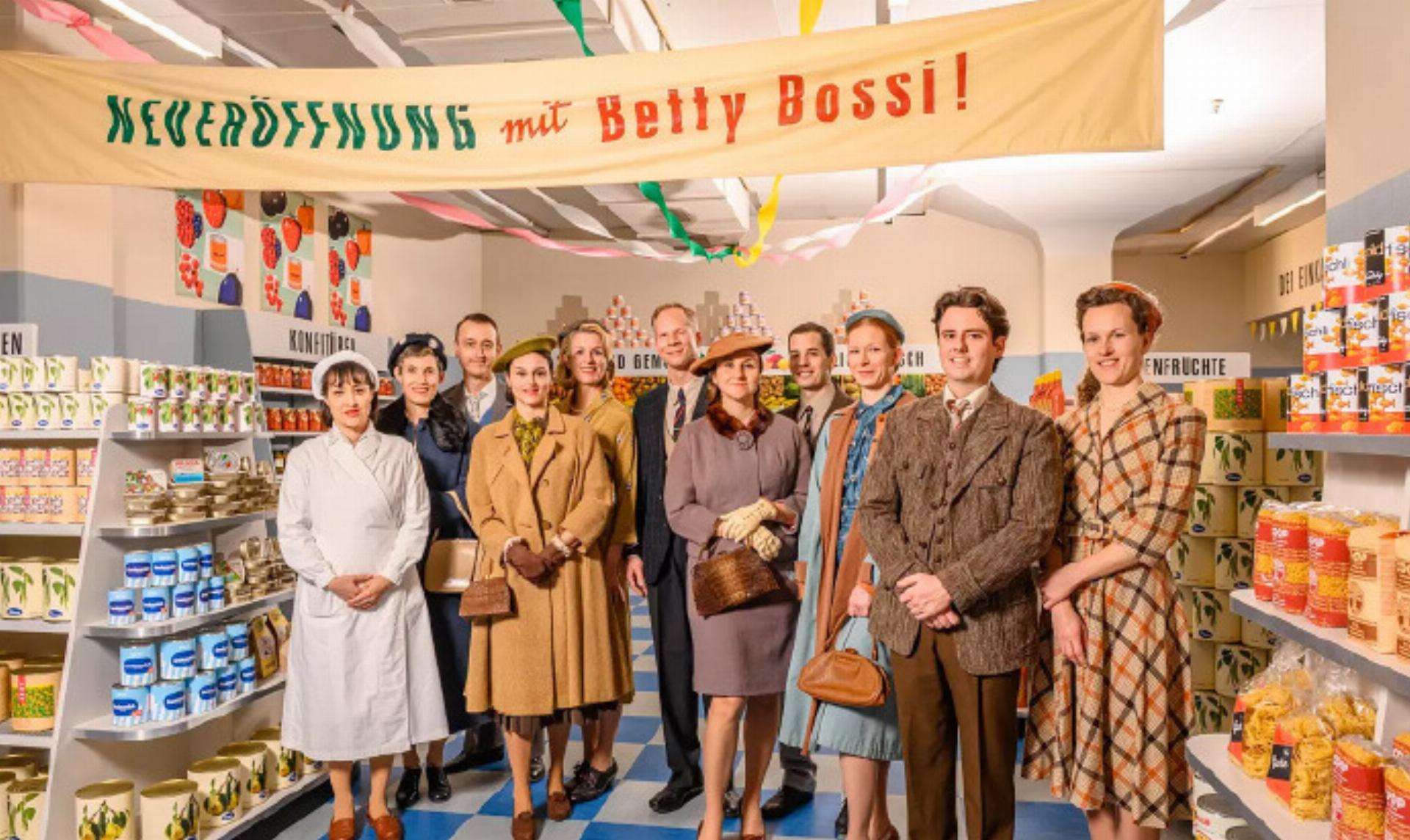 Real Bettys and Bossis on Set
Twenty-three Betty Bossi and Coop employees, along with many customers, were invited to appear as extras. With Audrey Hepburn–style updos, neat buns, suspenders, and sharply parted hair, the 1950s came to life, and between “Please don’t look into the camera!”, last-minute powdering, and Take 37, it became an unforgettable highlight for everyone involved. Photograph: © Christoph Kaminski - Das Bild wird blockiert. – Möglicherweise durch einen aktiven Adblocker.