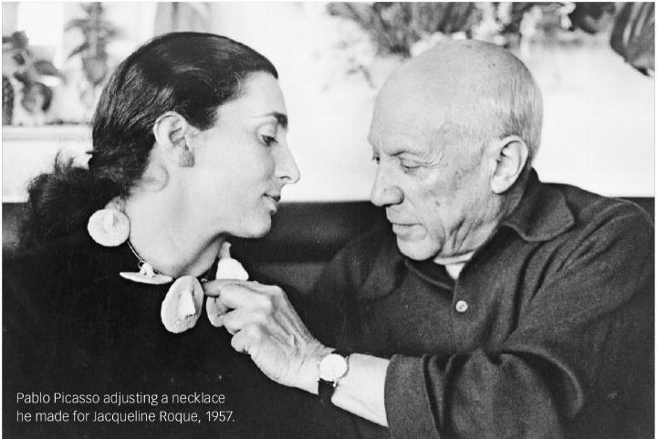 Pablo Picasso adjusting a necklace he made for Jacqueline Roque, 1957.